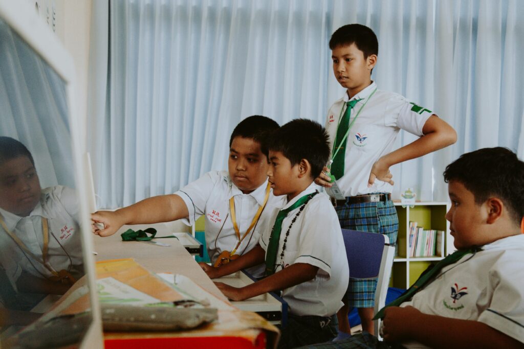 A group of boys in school uniforms collaborate on a computer project indoors.